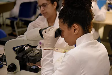 2022 Aluna do curso de Análises Clínicas utilizando microscópio em aula no laboratório